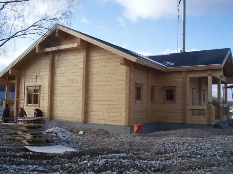Valmis palkmaja katusealuse verandaga sügisõhtul