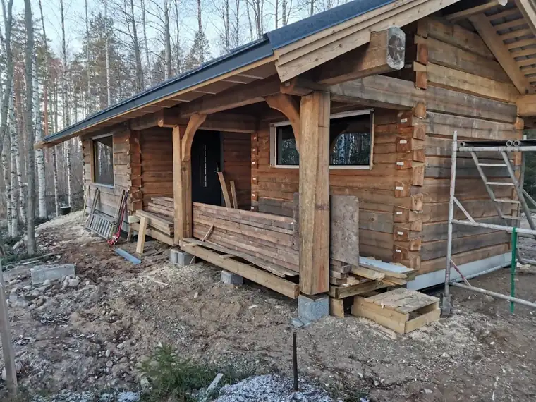 Ümarpalkmaja verandasammastega sügisesel platsil