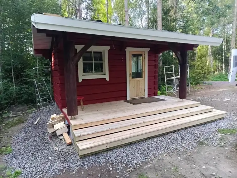 Punaseks värvitud kõrvalhoone varikatuse ja terrassiga