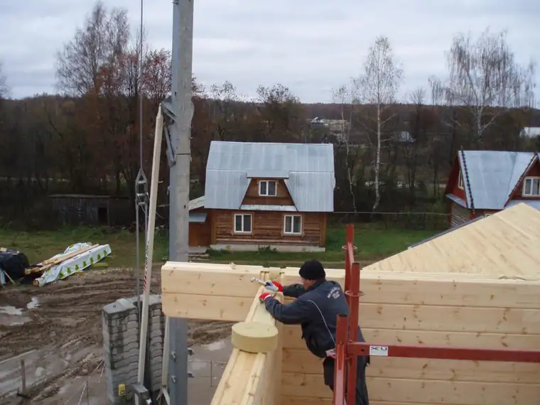 Mees sobitab palki seinale, taustal küla